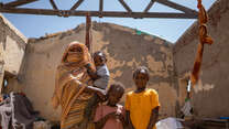 A Sudanese family pose for a photo in the ruins of a building destroyed by conflict.