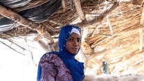 A woman poses for a photo in a makeshift shelter in Mali.