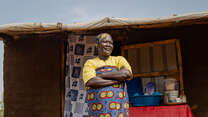 A woman stands with her arms folded outside in Uganda.