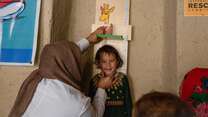 A smiling child in Afghanistan has their height measured.