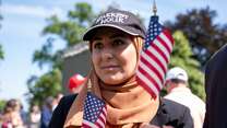 A newly naturalized American citizen has her portrait taken. U.S. flags are featured in the background.