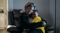 Bonfils mother, Nyabeza Nyabigazi, sits with her son, hugging him.