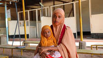 Damac sits with her daughter, Nimo, who is receiving EU-funded treatment for malnutrition, as they wait for a routine nutrition check-up in Health Post L, in  Hagadera, Kenya.