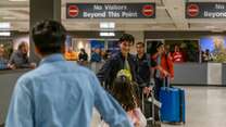 Standing in the airport arrivals, a father smiling at his two children embracing after being apart