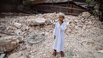 En liten pojke står mitt i rasmassorna efter jordbävningen i Myanmar 2025.