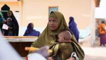 Eine Mutter hält ihr schlafendes Kind in den Armen, während sie eine IRC-Gesundheitsklinik in Somalia besucht.