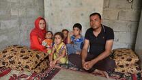 Naser and his family sit on cushions in a shelter after fleeing ISIS