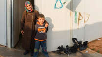 Jamalat Abd al-Raouf al-Hariri stands outside her home in Jordan's Zaatari camp with her seven-year-old son.