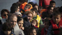 Syrian refugees approach the shores of Lesbos, Greece in an overcrowded rubber raft. 