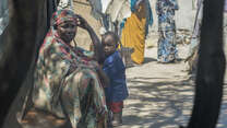Displaced woman sits with a child outside a tent in Mogadishu