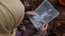 Syrian refugee woman holds a drawing
