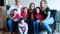 The Tlas family, refugees from Syria, pose for a photo with an IRC staff member in their new home in San Diego