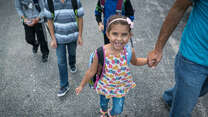 Jori holds her father's hand while walking to school