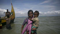 A Rohingya mother carries her child to shore after fleeing Myanmar's Rakhine State.