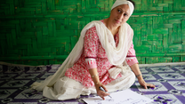 Razia Sultana sits on the tiled floor with a green background