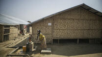 A Rohingya women pumps water outside a longhouse in Myanmar