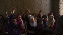 Girls raise their hands in a primary school classroom in Afghanistan