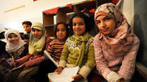 Six Syrian refugee children sit in a row,