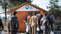Refugees queue at the IRC's partners InfoParks information point.