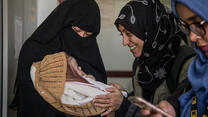 A mother brings her baby to an IRC health clinic in Yemen