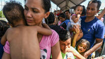A Honduran couple and their five children, heading to the U.S. in a caravan, wait to cross into Mexico