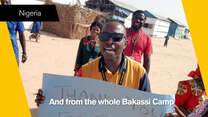 An IRC aid worker in Nigeria holds up a 'thank you' sign in a still from video thanking IRC donors