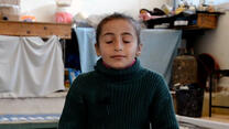 Eyes closed, Reem an 8-year-old girl in Syria, takes a deep breath while practicing mindfulness.