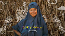 Nurta, who lives in Helowyn camp in Ethiopia, smiles. There is text on the photo that reads "sociable" in English and Somali. 
