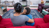 Angelina, an asylum seeker from Guatemala, sits on a red couch with her arms around her son at an IRC Welcome Center in Arizona.