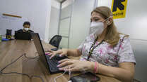 An IRC healthworker wearing a mask to protect herself from COVID-19 types at a laptop