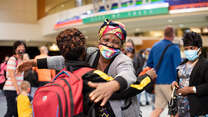 Wanyema Mitambo, wearing a mask, hugs her grandchild in the Boise Airport