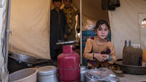 Three children at the entrance to a tent in Badghis, Afghanistan where their family is living after being displaced by drought.
