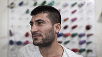 Mohamed Saleh Ismail stands in front of reels of thread in a tailoring workshop in Lebanon