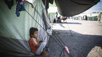 A little boy sits in the shade to escape the mid-day sun at the Alexandria refugee camp in northern Greece