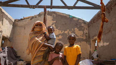A Sudanese family pose for a photo in the ruins of a building destroyed by conflict.
