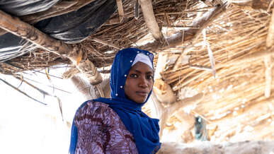 A woman poses for a photo in a makeshift shelter in Mali.