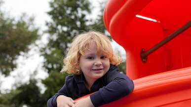 A child smiles while playing at a playground.