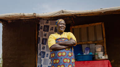 A woman stands with her arms folded outside in Uganda.