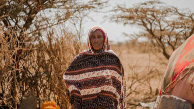 한 여성이 임시 거처 앞에서 앉아 있습니다.