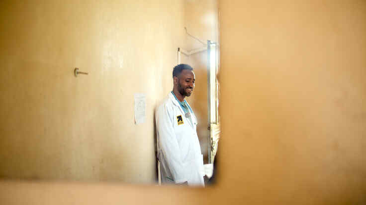 Ein Arzt lehnt sich an einer Wand an.