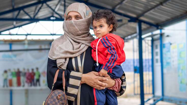 Eine syrische Mutter hält ihr Kind im Arm.