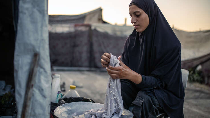 Tonårsflicka i Gaza tvätter kläder utomhus en tidig morgon i tätlägret där de bor.