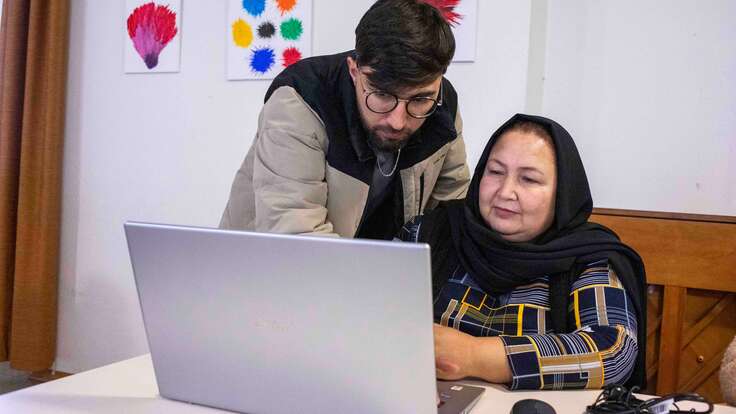 Afghanische Frau und junger Mann in Deutschland arbeiten gemeinsam am Laptop.