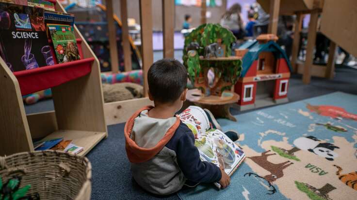 A young boy reads a book by himself at the IRC's Welcome Center in Phoenix, Arizona.