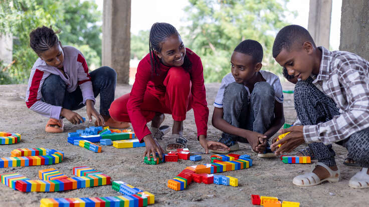 Fyra elever sitter på huk och arbetar med klossar vid sin skola i Etiopien.