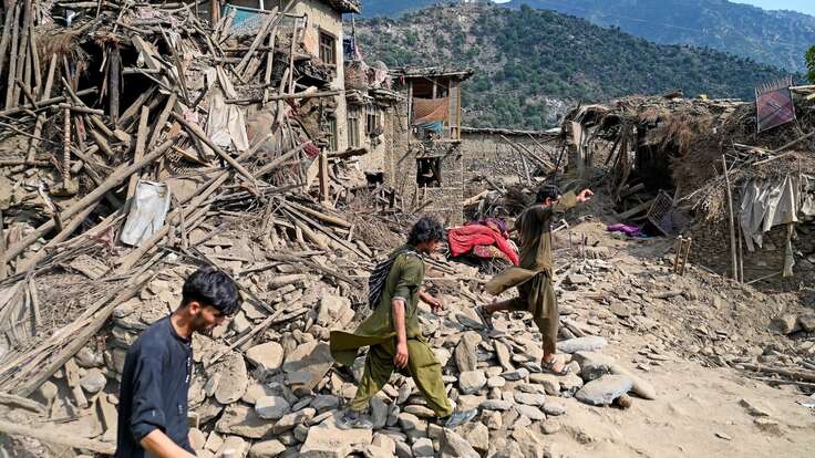 지진으로 무너진 잔해 위를 사람들이 걷고 있습니다.