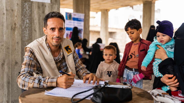 En familj står samlad runt en av RESCUE:s hälsoarbetare i en mobil hälsoklinik i Jemen.