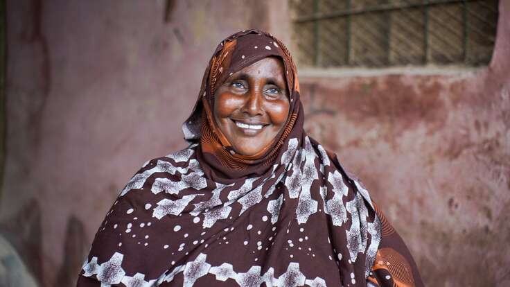Porträt einer lächelnden älteren somalischen Frau mit braun gemustertem Hijab.