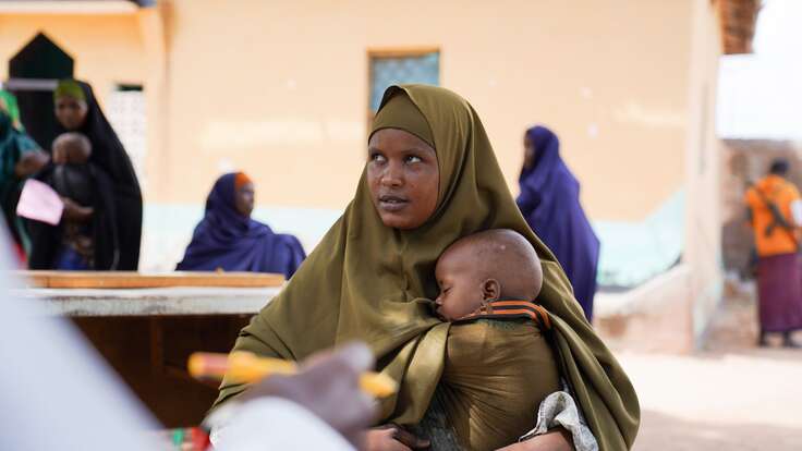 Eine Mutter hält ihr schlafendes Kind in den Armen, während sie eine IRC-Gesundheitsklinik in Somalia besucht.