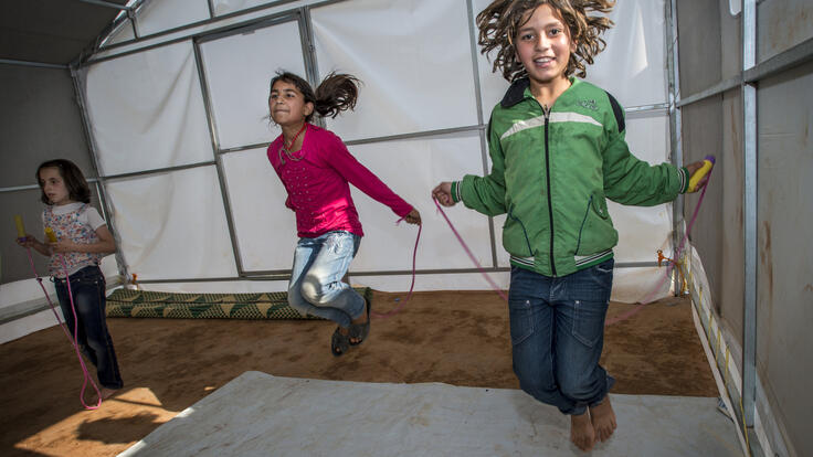 Two girls jump rope in a temporary classroom  in Idlib.